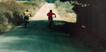 two boys racing their bikes away from the photographer
