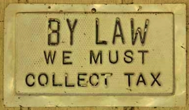 metal plate reads By Law We Must Collect Taxes